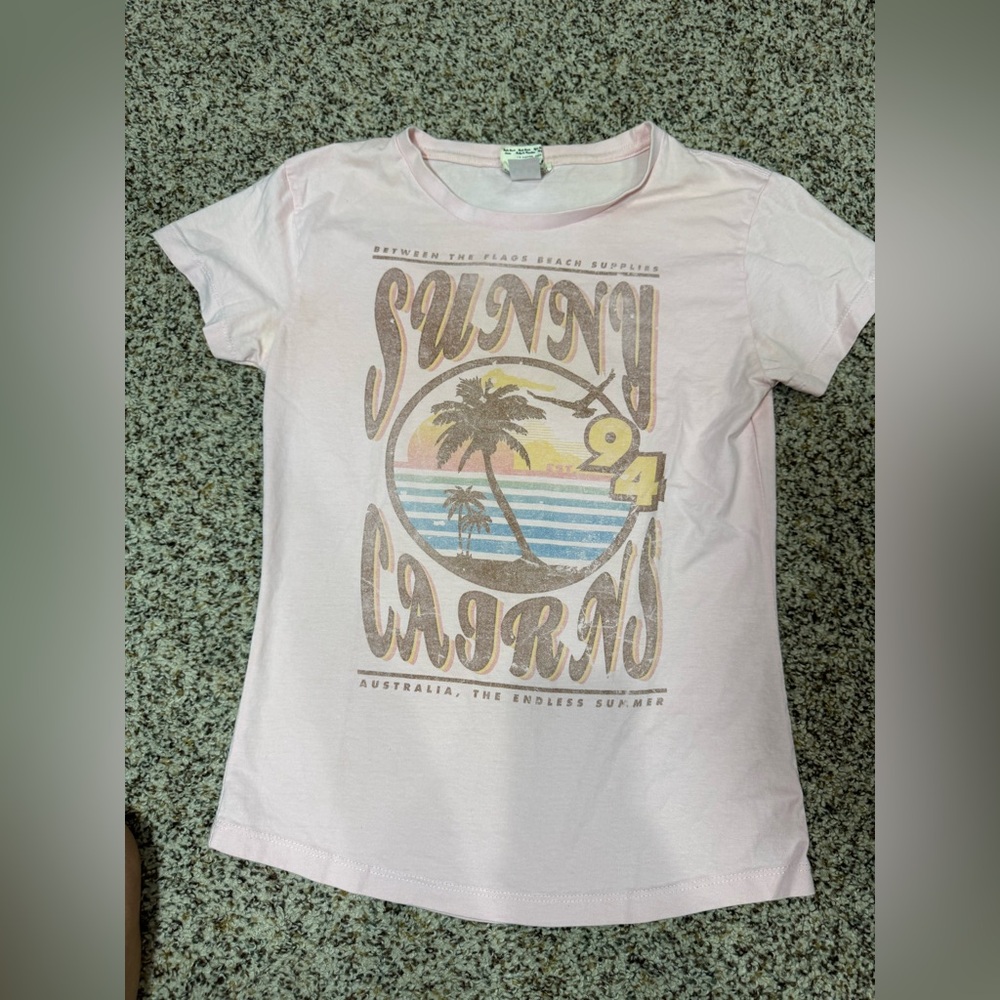 Sunny Cairns Women’s T-Shirt - Pink. Between the Flags